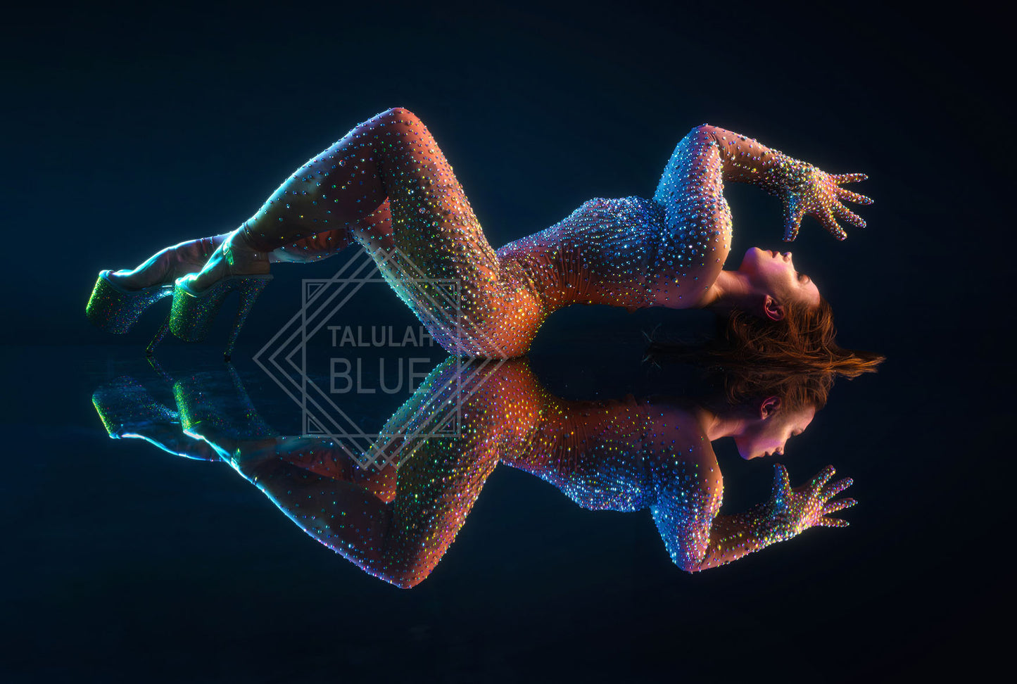 Person with glowing multicolor dots lying on a reflective surface against a black background Photo by Andre Pattenden Model Anna
