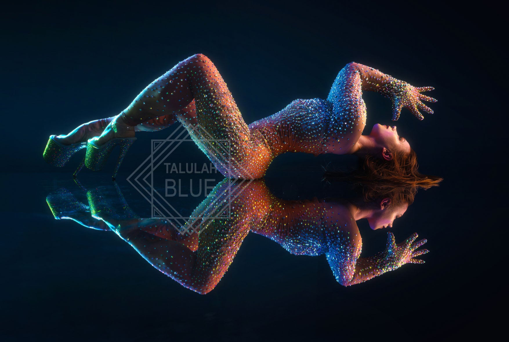Person with glowing multicolor dots lying on a reflective surface against a black background Photo by Andre Pattenden Model Anna
